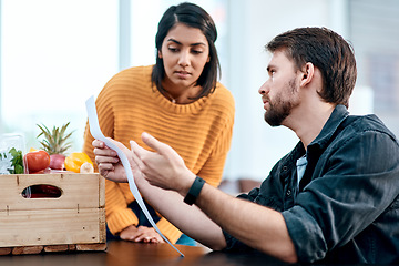 Image showing Unhealthy financial choices can make an unhealthy marriage. a young couple going through their receipts at home after buying groceries.