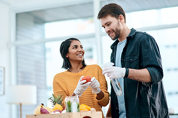Image showing Disinfecting your groceries, welcome to 2020. a young couple disinfecting their groceries at home.