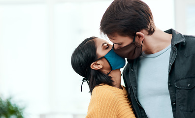 Image showing Flirting in 2020 Will you quarantine with me. a young couple kissing each other while wearing masks at home.