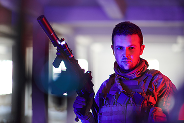 Image showing A professional soldier undertakes a perilous mission in an abandoned building illuminated by neon blue and purple lights