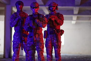 Image showing Soldier squad team walking in urban environment colored lightis