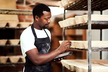 Image showing I found a great tool to help me keep track of orders. a man using a digital tablet while working in a bakery.