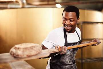 Image showing He bakes with passion. a male baker removing freshly baked bread from the oven.