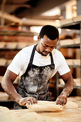 Image showing Everything is made with love and care. a male baker busy shaping dough at work.