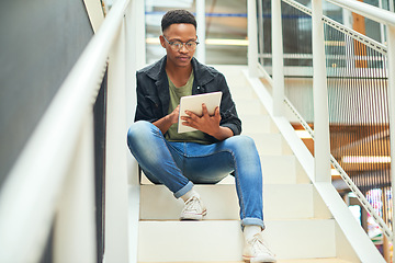 Image showing Whatever the task, technology will handle it. a young businessman using a digital tablet on the stairs of a modern office.