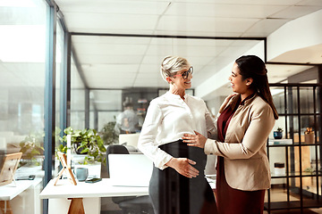 Image showing Looking forward to meeting the new team member soon. a businesswoman touching her colleagues pregnant belly in an office.