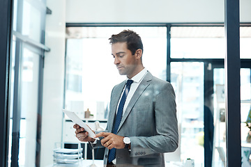 Image showing Im always in contact with my clients. a professional businessman using a digital tablet in his office.