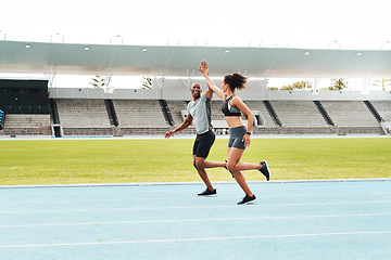 Image showing Yes We finished. Full length shot of two young athletes giving each other a high five during a run on a track field.