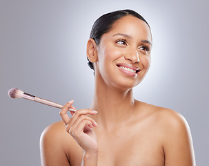 Image showing How should I do my makeup today. an attractive young woman standing alone in the studio and feeling playful while holding a makeup brush.