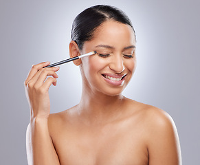 Image showing I never leave without eyeshadow. an attractive young woman standing alone in the studio and applying eyeshadow.