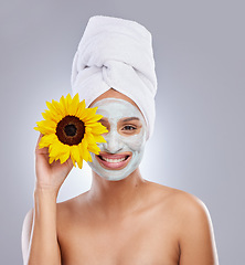 Image showing Skincare routines make me happy. an attractive young woman wearing a face mask and holding a sunflower over her eye in the studio.