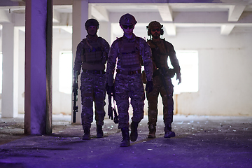 Image showing Soldier squad team walking in urban environment colored lightis