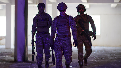 Image showing Soldier squad team walking in urban environment colored lightis