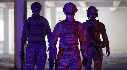 Image showing Soldier squad team walking in urban environment colored lightis