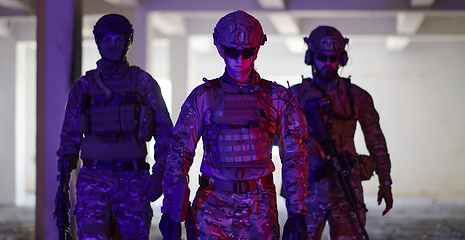 Image showing Soldier squad team walking in urban environment colored lightis