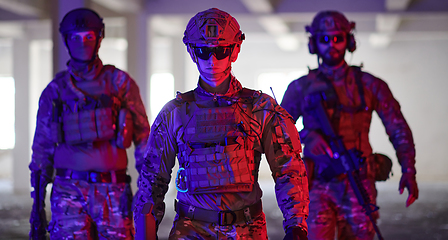 Image showing Soldier squad team walking in urban environment colored lightis