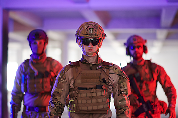 Image showing Soldier squad team walking in urban environment colored lightis