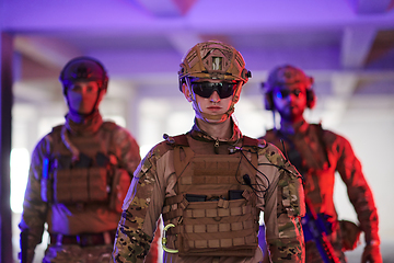 Image showing Soldier squad team walking in urban environment colored lightis