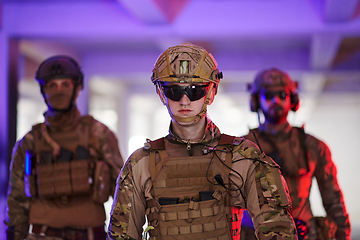 Image showing Soldier squad team walking in urban environment colored lightis