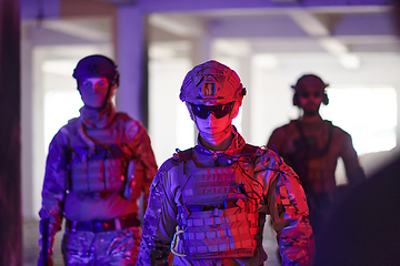 Image showing Soldier squad team walking in urban environment colored lightis