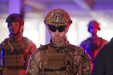 Image showing Soldier squad team walking in urban environment colored lightis