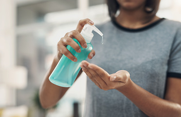 Image showing One squeeze squashes those germs. an unrecognisable woman disinfecting her hands with sanitiser at home.