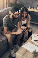 Image showing A handy device for home budgeting. a young couple sing a digital tablet while going through paperwork at home.