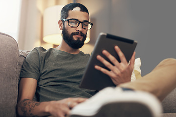 Image showing Loaded with all the info he needs. a young man using a digital tablet on the sofa at home.