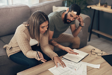 Image showing It might be time for some debt relief. a young couple looking stressed while going over paperwork at home.