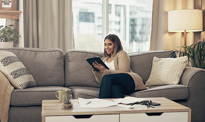 Image showing Budgeting is never a bore with apps like these. a young woman using a digital tablet while going through paperwork at home.