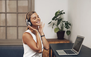 Image showing It doesnt feel like work when the musics this good. a young businesswoman using headphones and a laptop in a modern office.