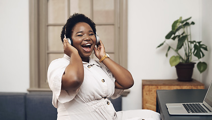 Image showing The future superstar of design. a young businesswoman using headphones and a laptop in a modern office.