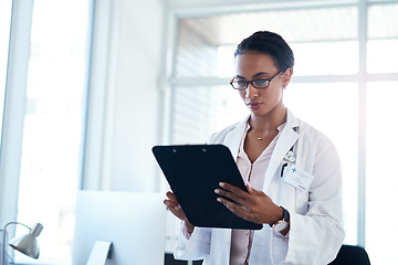 Image showing Getting a detailed look at her patients symptoms. a young doctor going over paperwork in her consulting room.