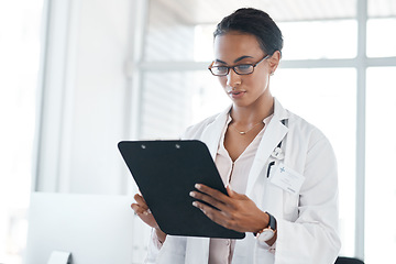 Image showing These stats look good to me. a female young doctor recording a patients information on a clipboard.