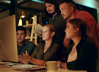 Image showing We never missed a deadline and were not starting now. a group of businesspeople looking at something on a computer in an office at night.