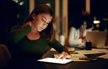 Image showing Ive been sitting like this for hours. a businesswoman experiencing neck pain while using a digital tablet in an office at night.