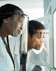 Image showing Applying their great minds. two scientists wearing face shields while working together in a lab.