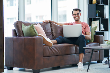 Image showing Social media is a real popularity booster for your brand. a young man using a laptop while relaxing on a sofa.