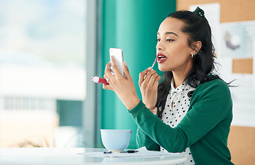 Image showing The more you grow, the more you glow. a young businesswoman applying lipstick using a smartphone in a modern office.