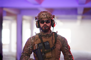 Image showing A professional soldier undertakes a perilous mission in an abandoned building illuminated by neon blue and purple lights