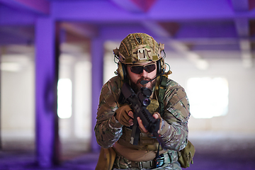 Image showing A professional soldier undertakes a perilous mission in an abandoned building illuminated by neon blue and purple lights