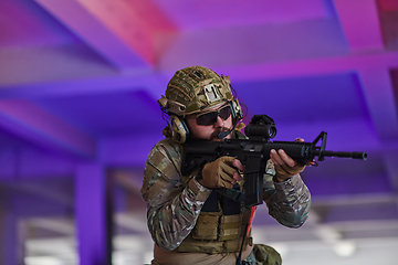 Image showing A professional soldier undertakes a perilous mission in an abandoned building illuminated by neon blue and purple lights