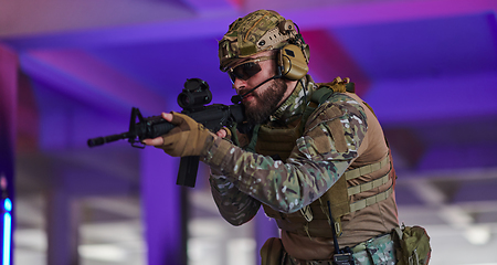 Image showing A professional soldier undertakes a perilous mission in an abandoned building illuminated by neon blue and purple lights