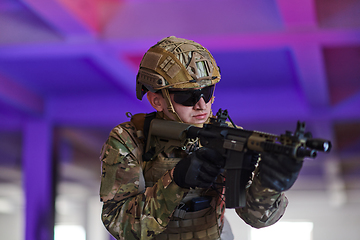 Image showing A professional soldier undertakes a perilous mission in an abandoned building illuminated by neon blue and purple lights