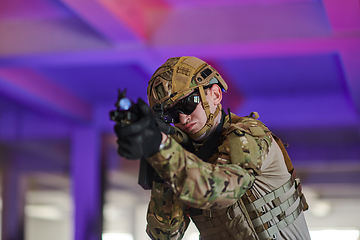 Image showing A professional soldier undertakes a perilous mission in an abandoned building illuminated by neon blue and purple lights