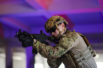 Image showing A professional soldier undertakes a perilous mission in an abandoned building illuminated by neon blue and purple lights