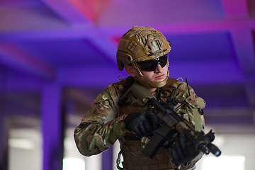 Image showing A professional soldier undertakes a perilous mission in an abandoned building illuminated by neon blue and purple lights