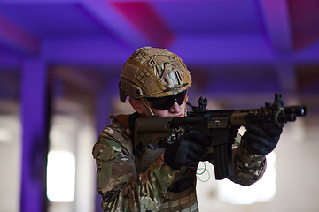 Image showing A professional soldier undertakes a perilous mission in an abandoned building illuminated by neon blue and purple lights