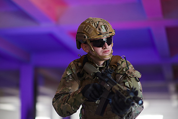 Image showing A professional soldier undertakes a perilous mission in an abandoned building illuminated by neon blue and purple lights