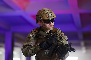 Image showing A professional soldier undertakes a perilous mission in an abandoned building illuminated by neon blue and purple lights